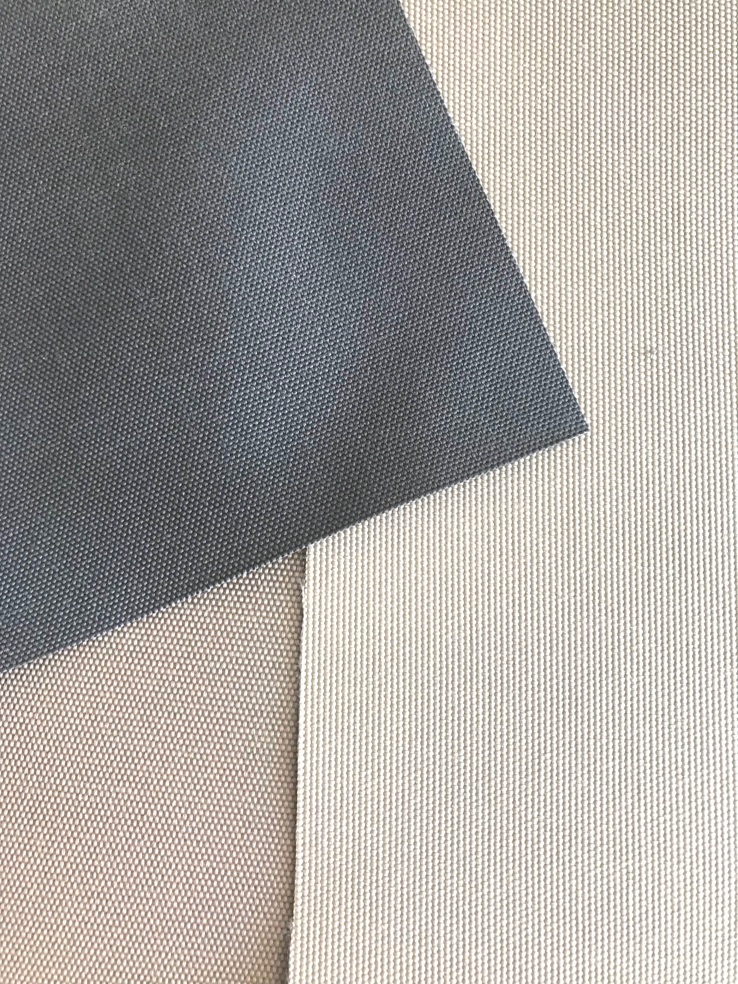 Detail tří vzorků venkovních potahových materiálů v šedé, béžové a krémové barvě